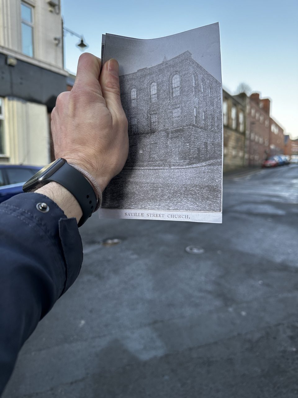 Old photo of Saville Street Methodist Chapel held up to current site